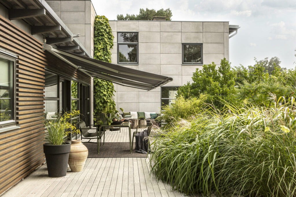 Gråa terrassmarkiser över uteplats.