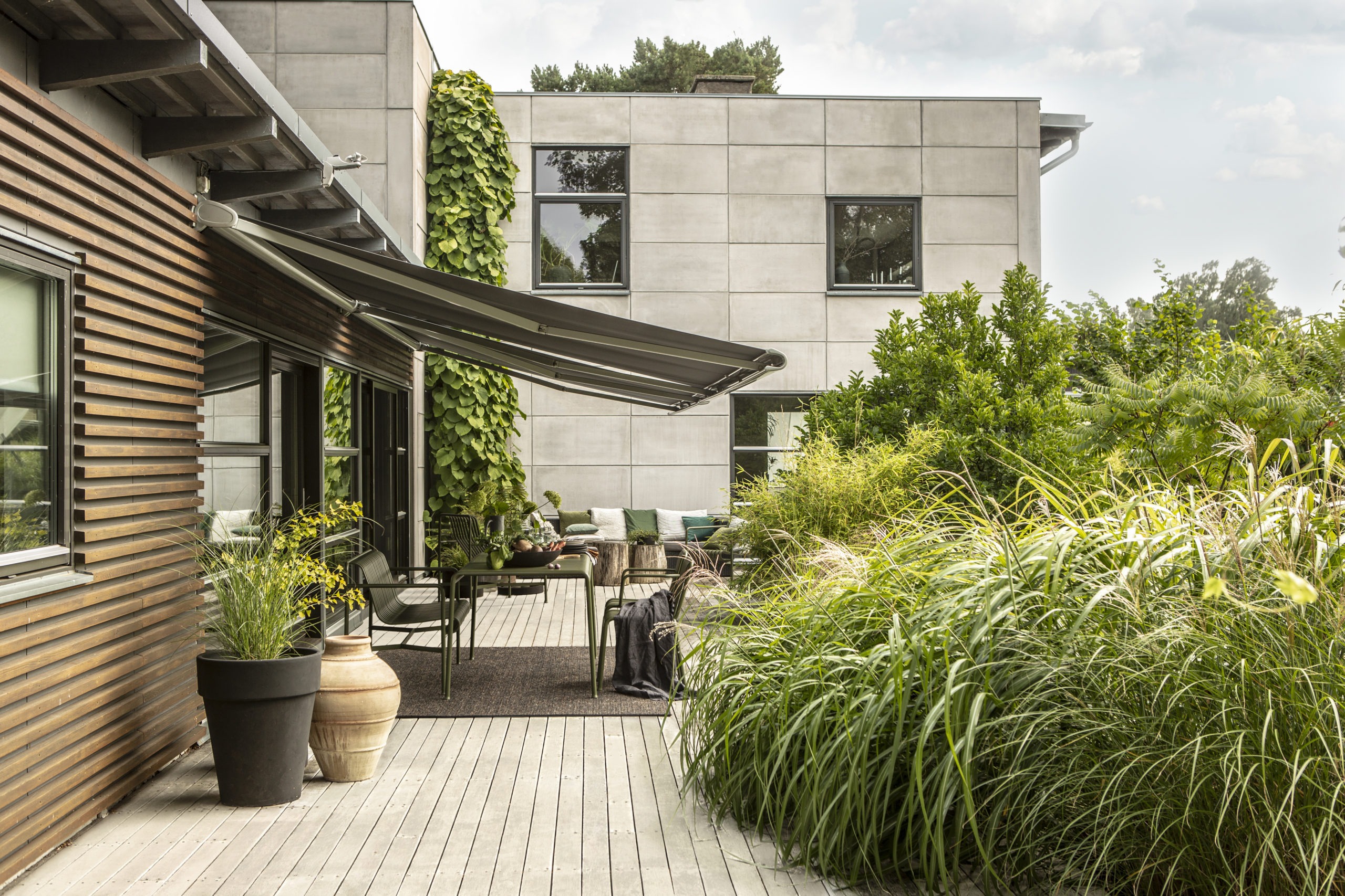 Gråa terrassmarkiser över uteplats.