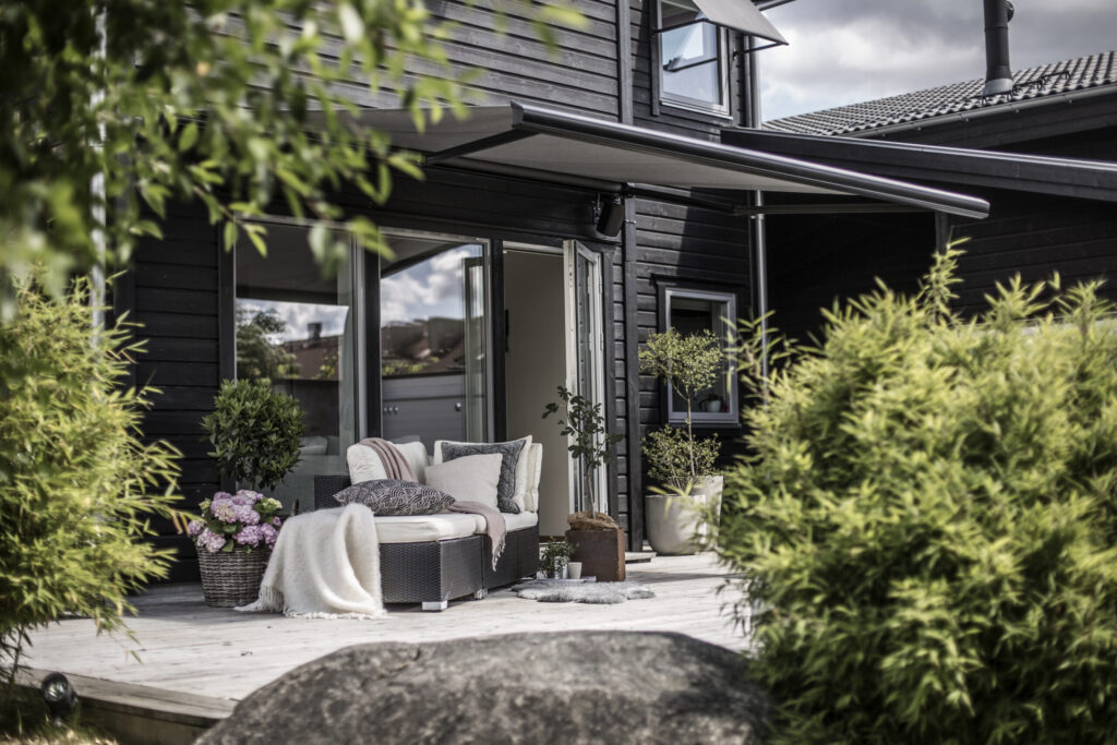 Grå terrassmarkis på svart villa.