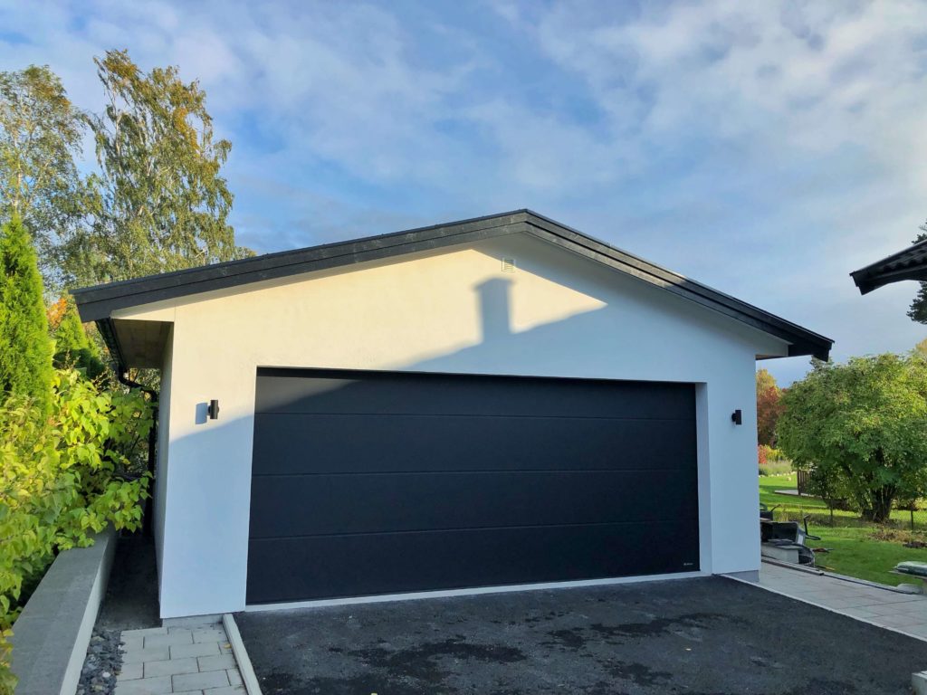 Grå garageport i vitputsat garage.