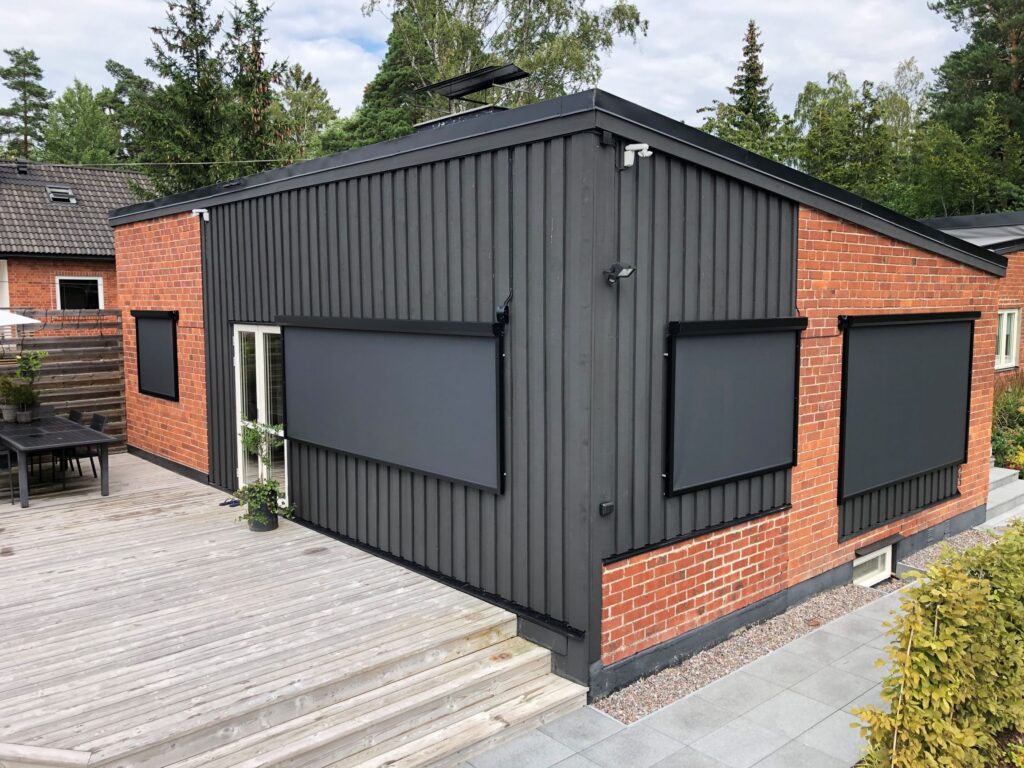 Svarta zipscreens på villa med tegel- och träfasad.