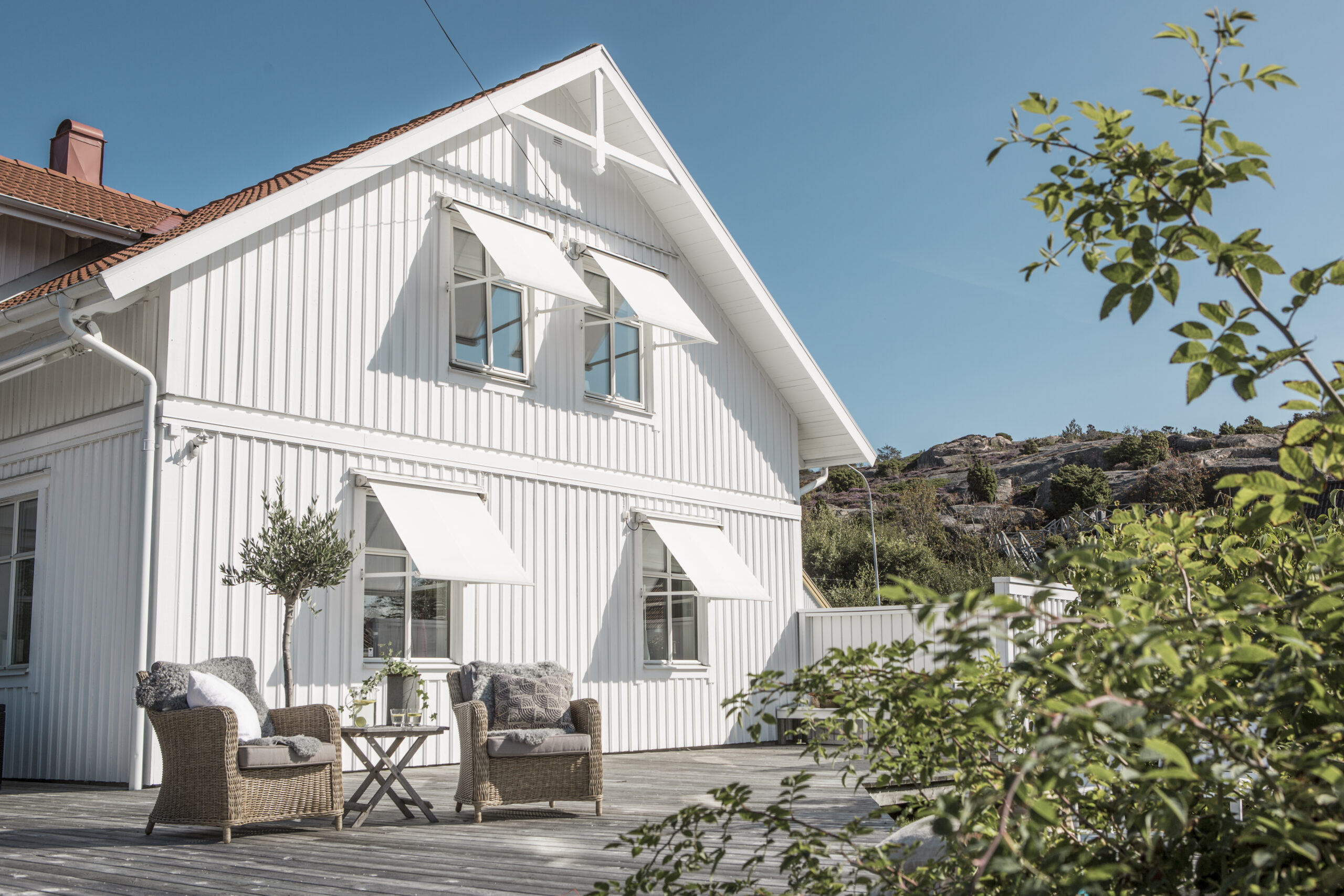 Vita fönstermarkiser på vit villa.