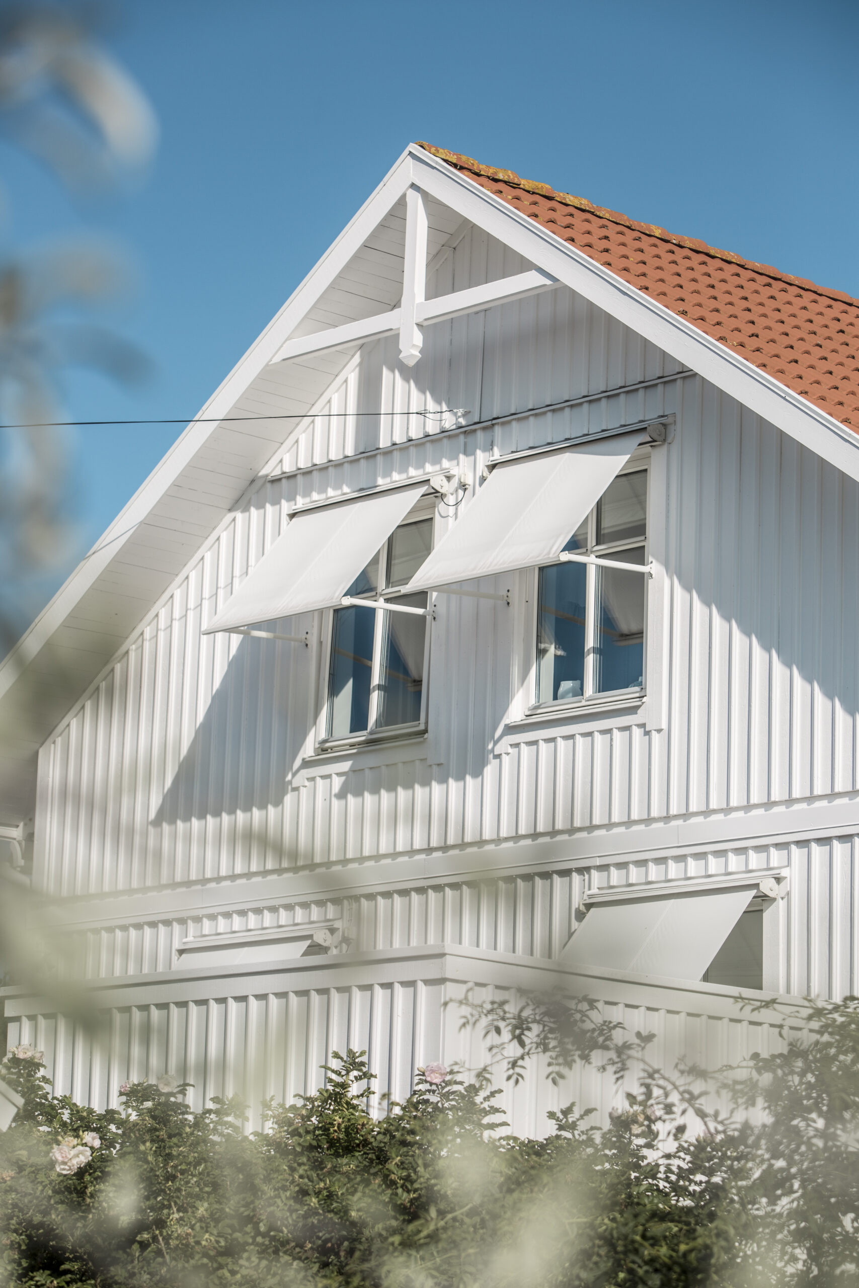 Vita fönstermarkiser på vit villa.
