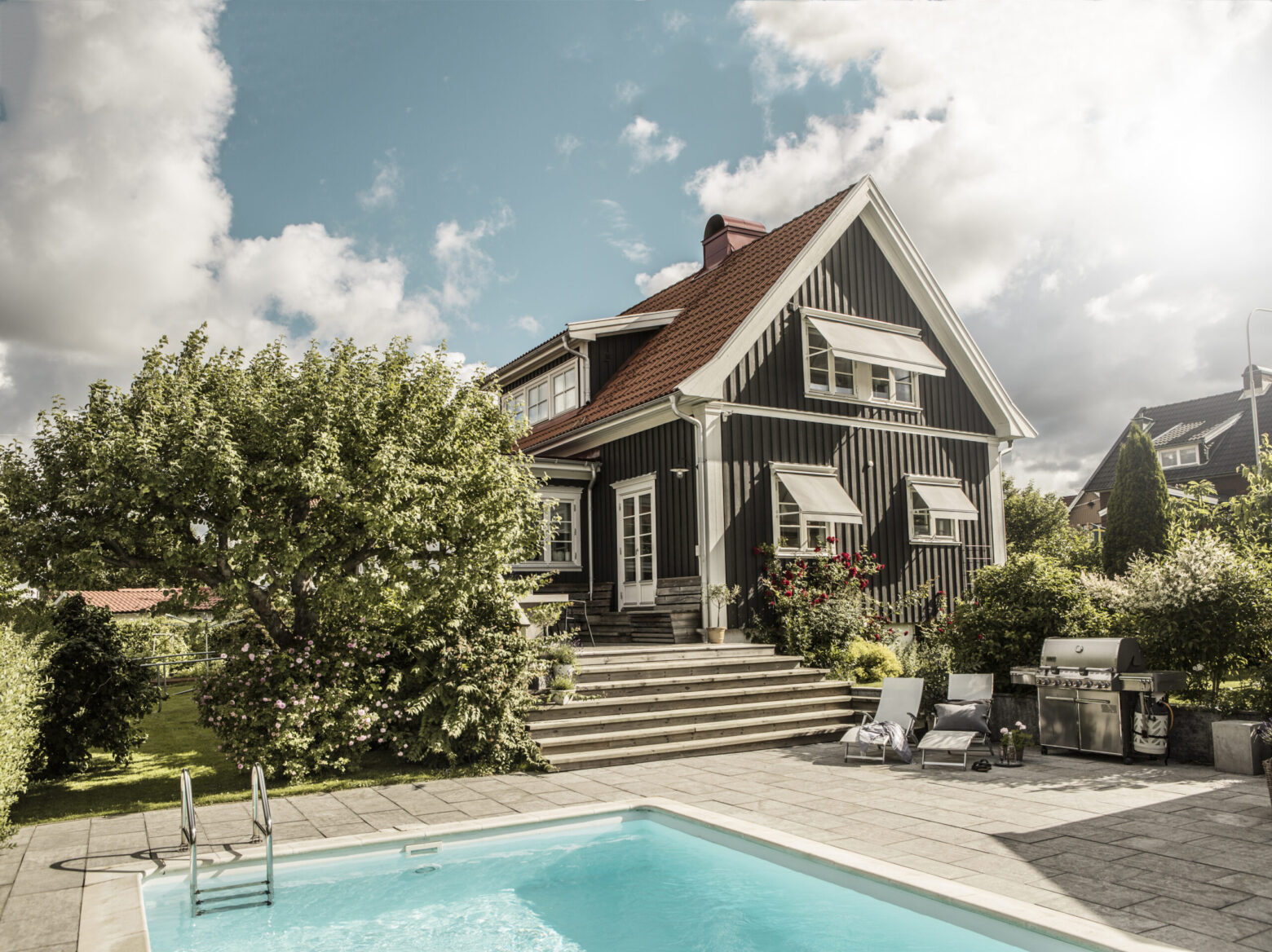 Gråa fönstermarkiser på svart villa.