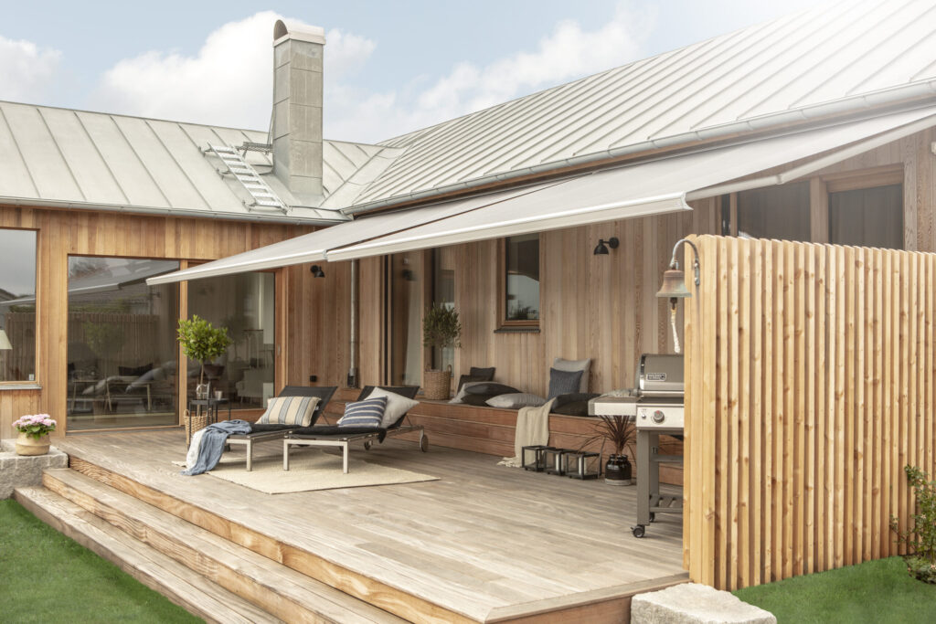 Två terrassmarkiser på villa med träfasad.