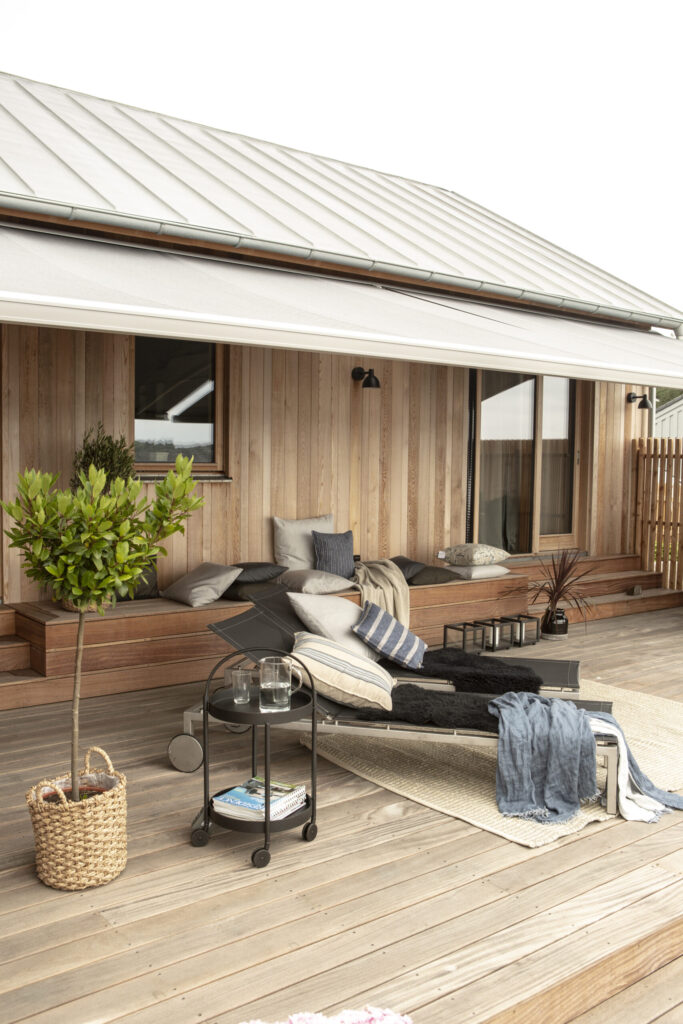 Terrassmarkis på villa med träfasad.