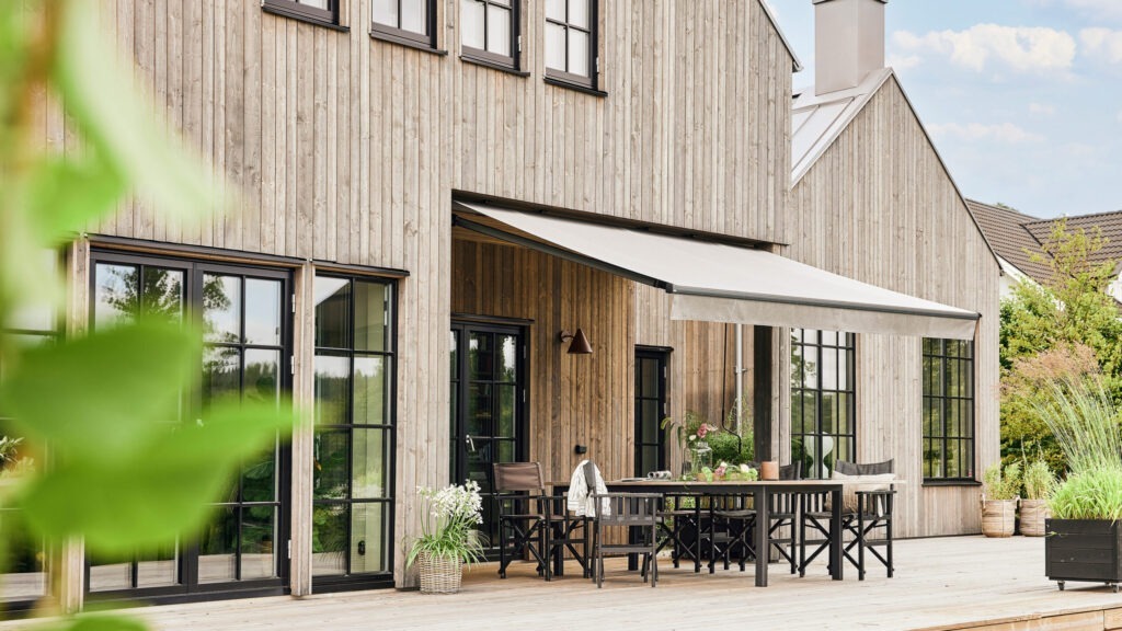 Terrassmarkis på villa med träfasad.