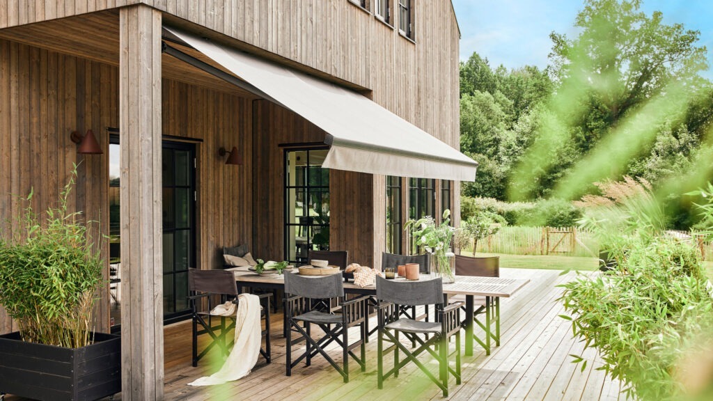 Terrassmarkis på villa med träfasad.