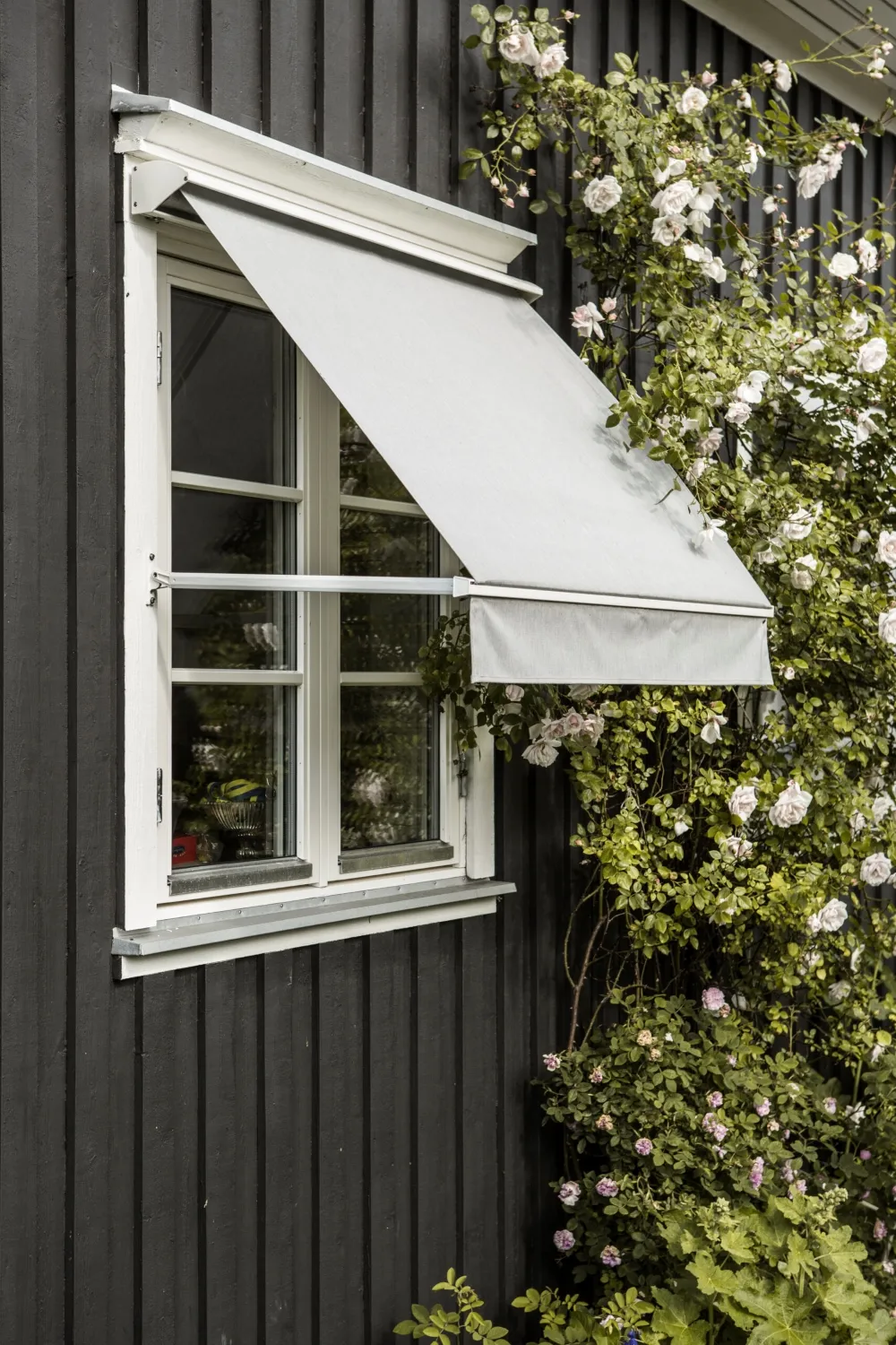 Grå fönstermarkis på svart villa.
