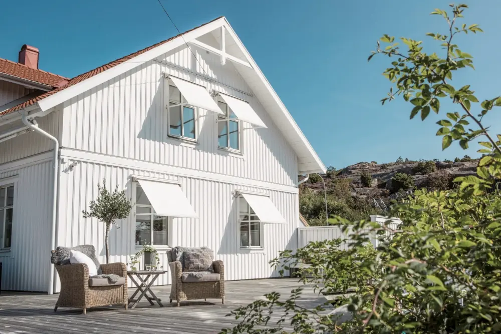 Vita fönstermarkiser på vit villa.