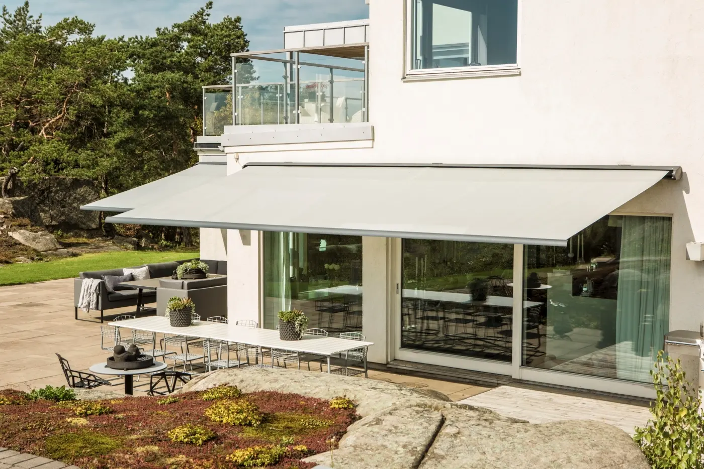 Terrassmarkiser på vitputsad fasad.