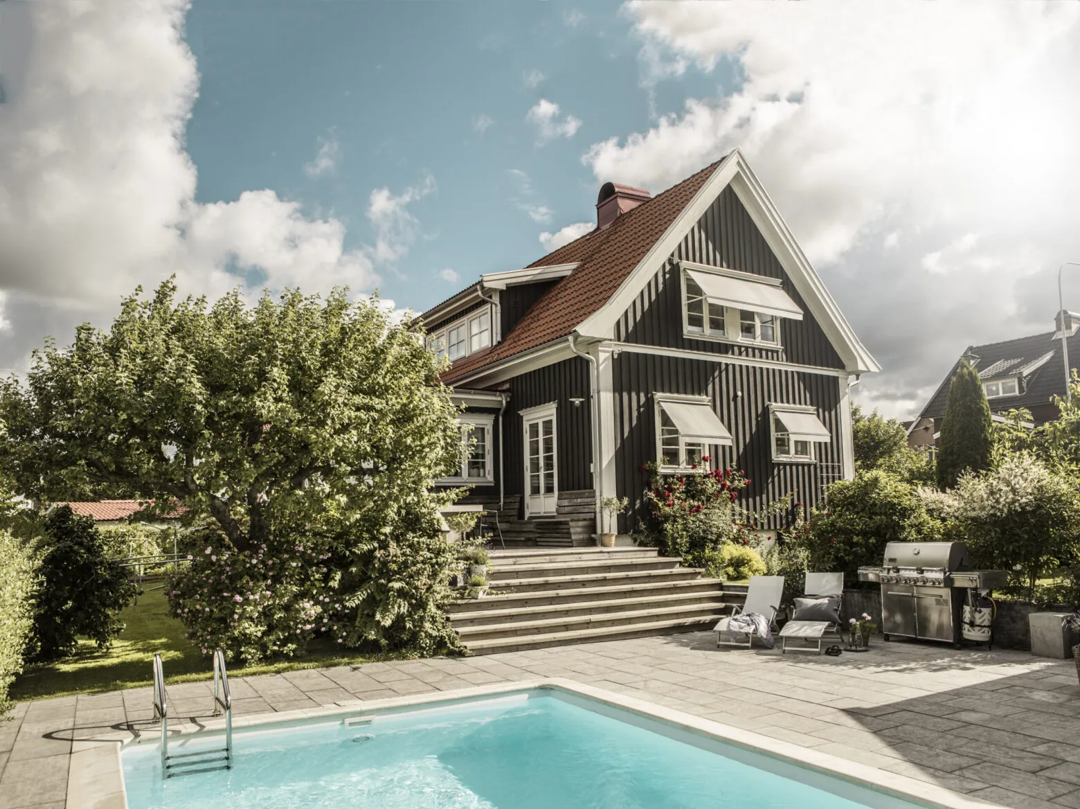 Svart villa med fönstermarkiser.