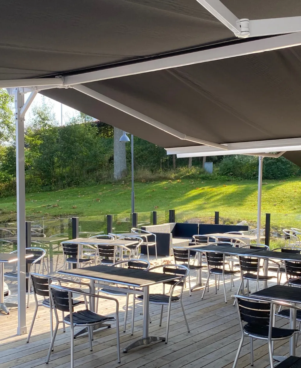 Fristående markis över uteservering med glasräcke runt om.