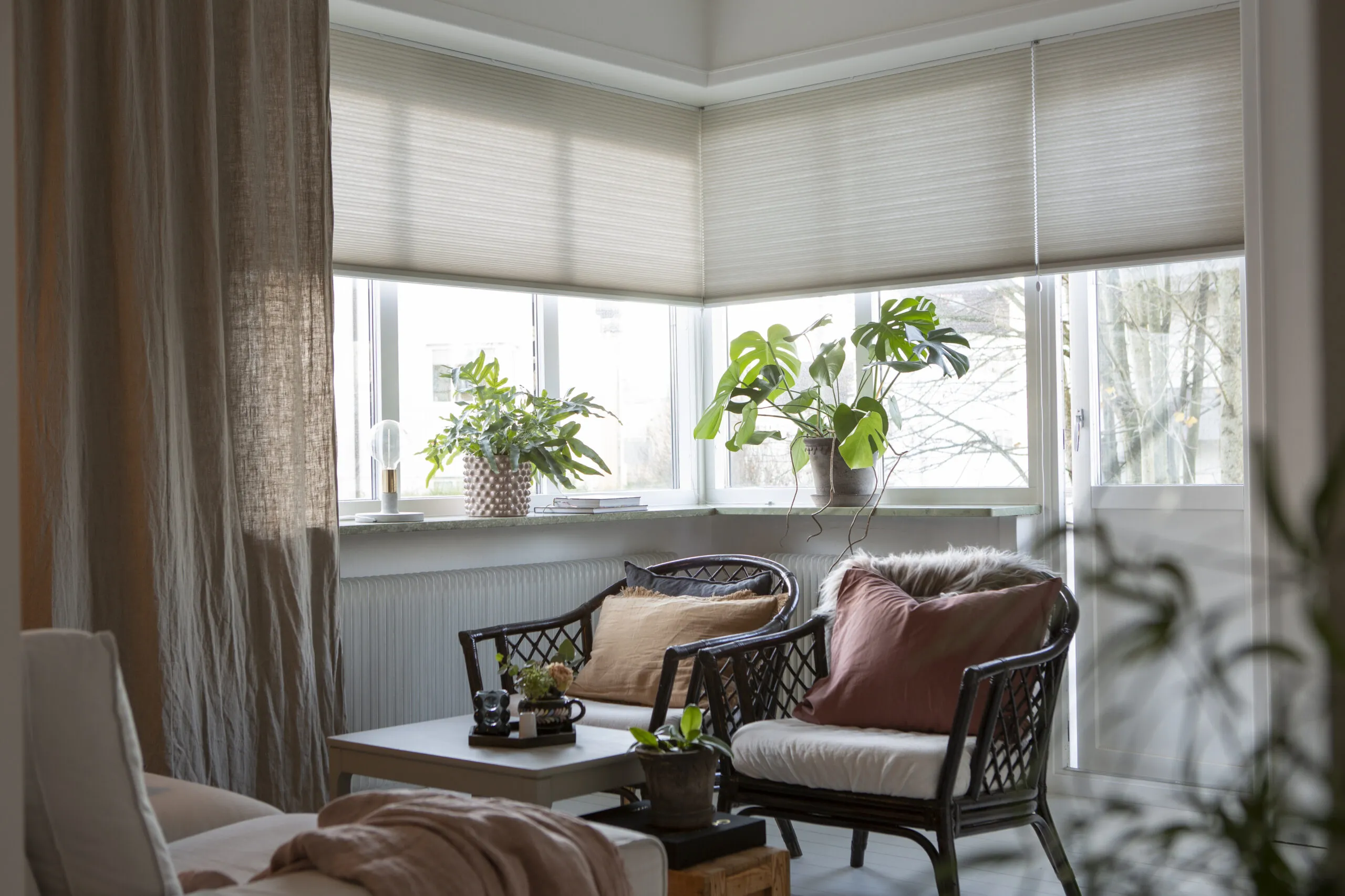 Beigea duettegardiner och gardin i vardagsrum.